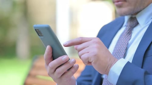 Close Up of Businessman Using Phone while Sitting Outdoor
