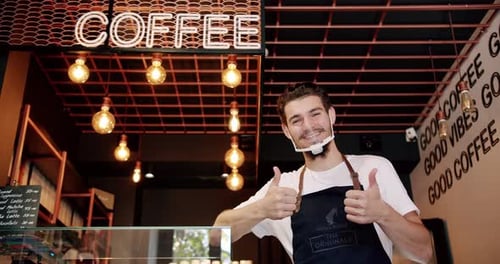 Content Young Guy Smiling During Work in Coffee Shop