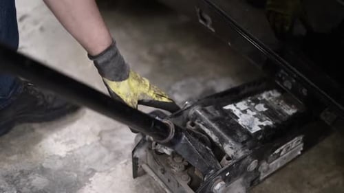 Slowmotion bokeh shot of a mechanic placing a car jack and jacking