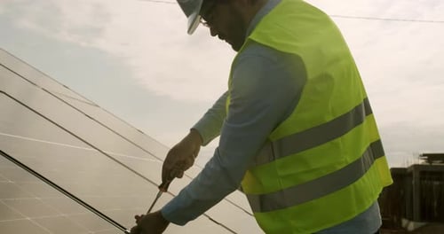Man Working on Solar Panels with Screwdriver