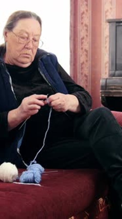 Old Woman Pensioner Home Knits Wool Socks Sitting on the Sofa Elderly Lady Hobby
