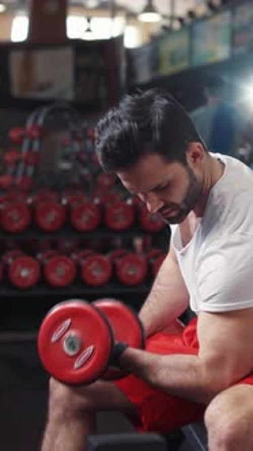 A Focused Workout A Determined Man is Intently Lifting a Dumbbell in a WellEquipped Gym Space