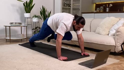 Hombre haciendo ejercicio de alpinista siguiendo un Vídeo tutorial en interiores