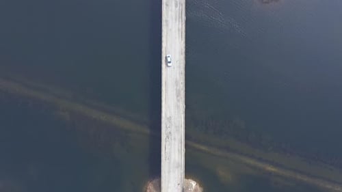 Slow motion aerial view of a bridge crossing a lake from a drone
