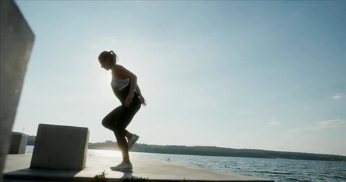 Sportswoman Jumping on Cube on Embankment