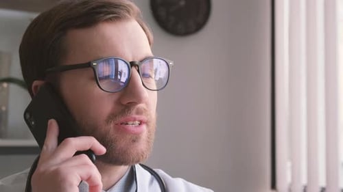 Young Handsome Doctor Talking on the Phone in His Office
