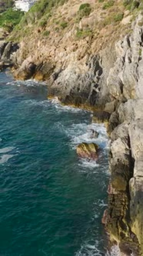 Vertical Video Scenic Mediterranean Coastline With Azure Waves Crashing Against White Rocky Cliffs