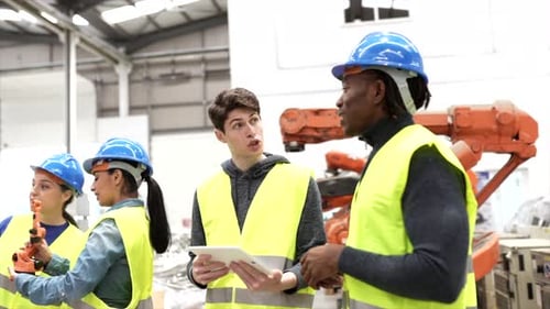 Modern factory: Male engineer project manager standing wearing safety jackets, helmets, working in w
