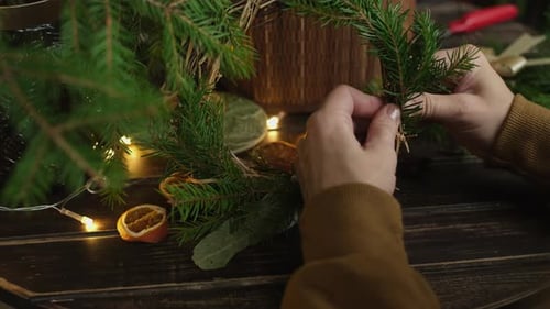Hands Assembling Christmas Wreath with Pine and Citrus