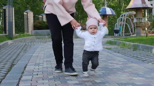 Parent Guides Infant Walking on Cobblestone Path