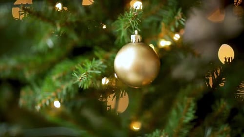 Gold Christmas Ball And Lights Hanging On A Christmas Tree. - close up shot