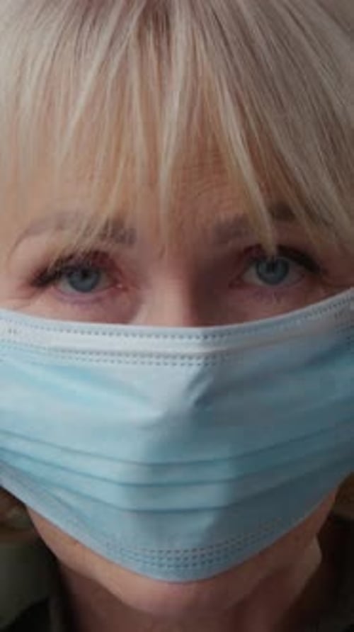 Portrait Ill Sick Caucasian Old Woman Putting on Facial Medical Mask Indoors Looking at Camera