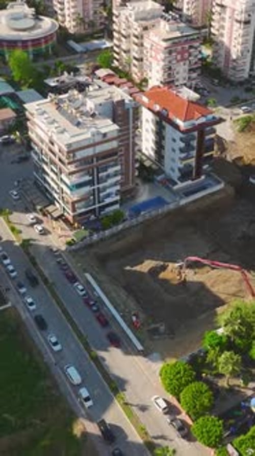 Trabajadores de vídeo vertical que operan maquinaria pesada en una obra de construcción muy transitada