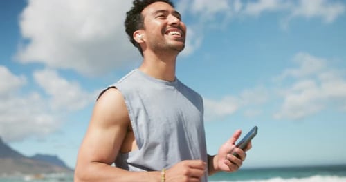 Earphones, dancing and happy man with phone on beach, listening and playlist for morning exercise
