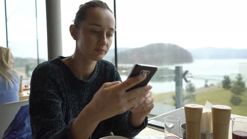 Woman With Smartphone Drinking Cocktail In Cafe