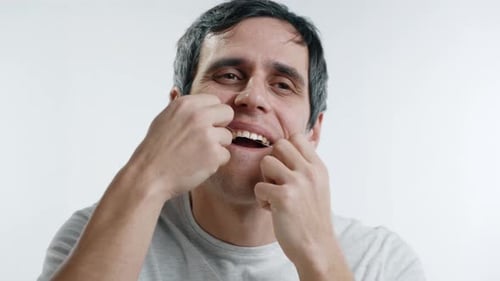 Hombre que se limpia los dientes con hilo dental para la higiene bucal