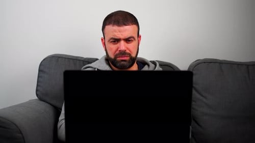Man Sitting on Couch Using Laptop