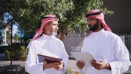 Two emirati businessmen wearing traditional saudi arabia