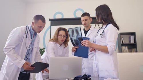 Team of Four Doctors Discusses the Results Chest XRay Scan of Patient in Consulting Room of Hospital