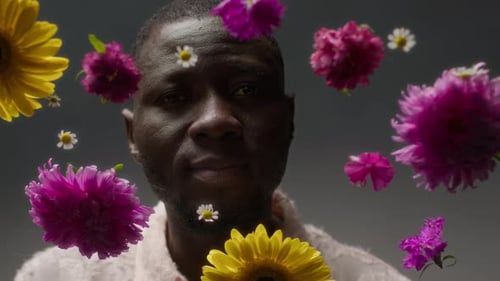 Studio Portrait of Black Man Amongst Vibrant Pink and Yellow Flowers