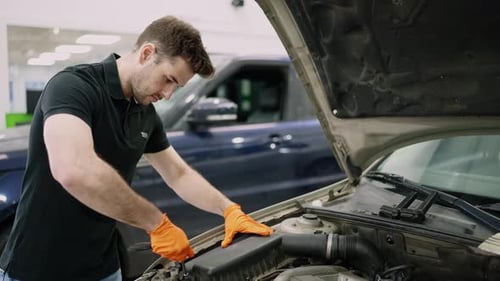 Mécanicien inspectant le compartiment moteur de la voiture dans un atelier de réparation automobile