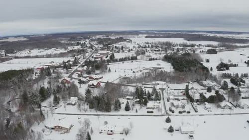 Blanket of new white snow on small rural town with barren trees. Aerial view from drone panning righ