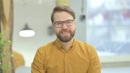 Smiling Man Waving and Talking in Office