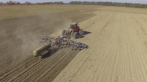 Big red tractor working on the field cultivating and applying nitrogen ASP