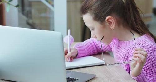 Girl Studying with Laptop and Notebook Indoors