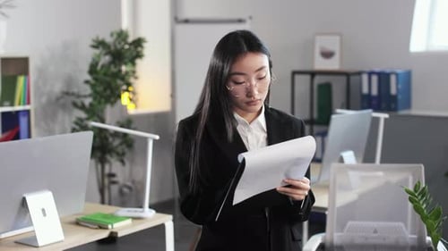 Asian Female Office Worker Writing on Clipboard