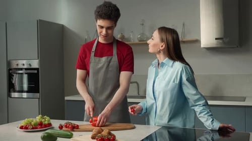 Una pareja joven prepara una ensalada saludable en una cocina moderna durante la noche