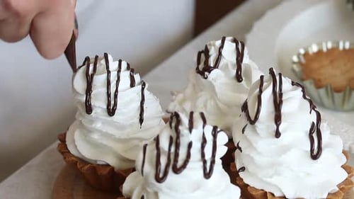 Eine Frau legt Schokolade auf Buttercreme. Aus einem Spritzbeutel. Macht einen Kuchenkorb. Nahaufnahme.