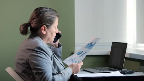 Mature Lady Office Worker Talks with Colleague on Smartphone