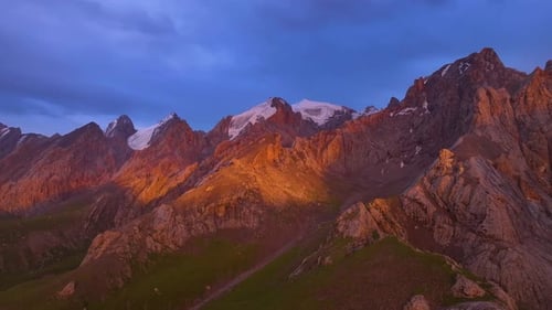 Sunset illuminating rugged mountain peaks with snow