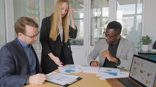 Ethnic diverse team brainstorming in office, discussing startup project.
