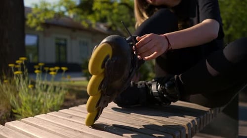 young beautiful girl in park tying laces on roller skates before skating workout active lifestyle