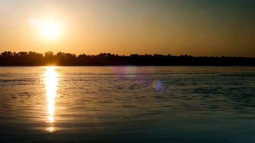 Sunset Behind The Trees On The Opposite Bank Of The River. Lens Flare