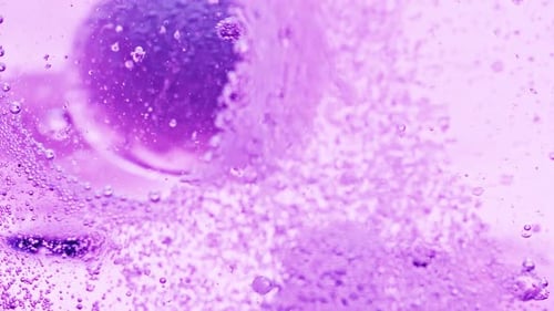 Makroaufnahme von vielen kleinen violetten Blasen, die im Wasser funkeln, und einer großen Blase, die aus