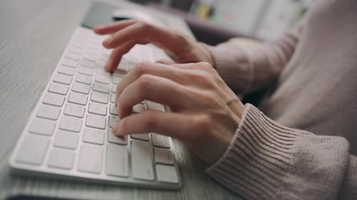 Female programmer typing on wireless keyboard in bright modern office