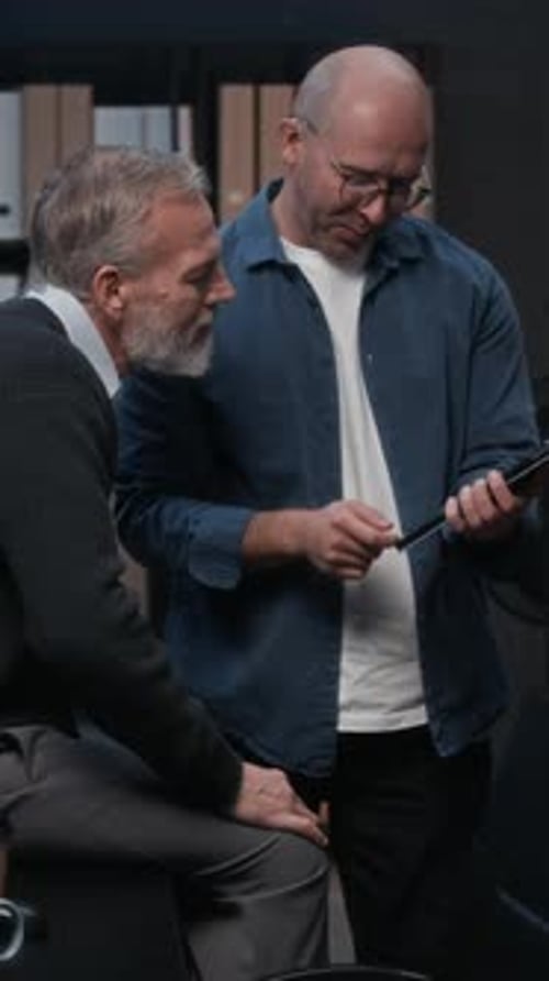 Vertical de dois colegas de cibersegurança discutindo dados usando tablet digital