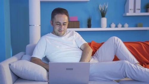 Man Relaxing on Couch Using Laptop at Home