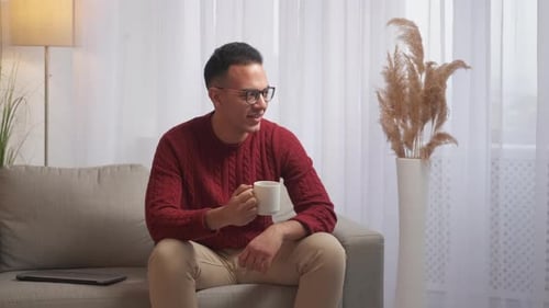 Man Drinking Coffee and Relaxing on Couch
