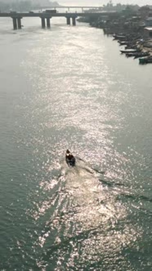 Drone suivant un bateau de pêche entre les îles près du pont au Vietnam par une journée ensoleillée
