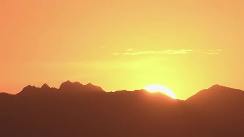 Siluetas de montaña con una colorida puesta de sol vívida en el cielo nublado. Lapso de tiempo