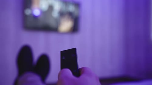 Adult Holding Remote Control While Watching TV
