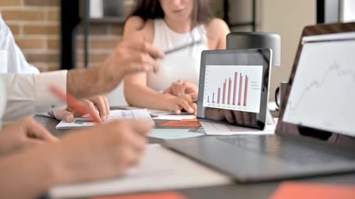 Three people are working and talking in the office. Gadgets and papers with graphs and information