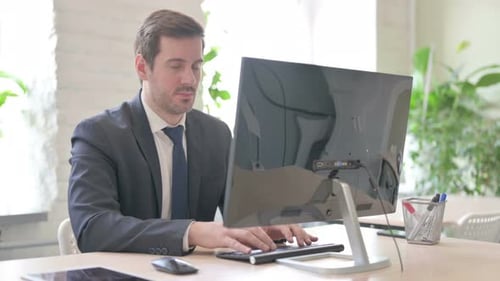 Man in Suit Working at Computer in Office