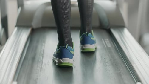 Sportlerfüße und Sportschuhe trainieren im Fitnessstudio auf einem Laufbandgerät