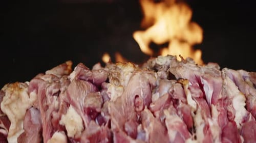 Raw Meat Stacked High with Flames in Background