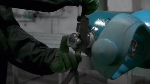 Close Up of Worker in Gloves Turning Gas Cylinder Valve Clip Industrial Background of the Factory